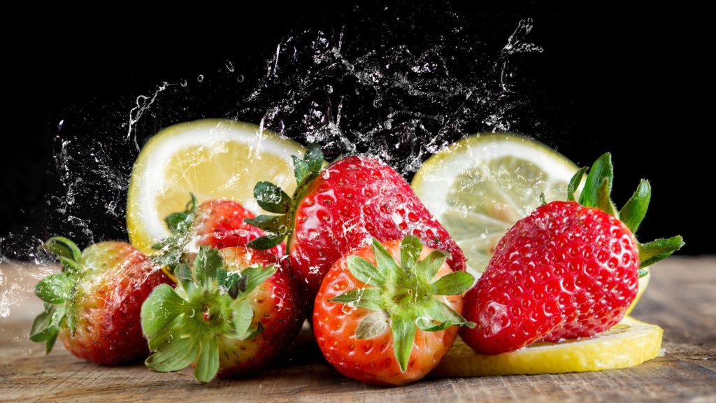 Fresh strawberries with lemons splashing in water with black background strawberry wallpapers for laptop