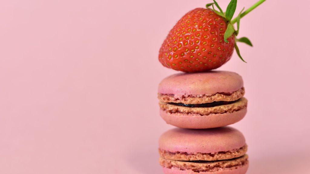 Red juicy strawberry on top of macaroons with baby pink background strawberry wallpapers for laptop