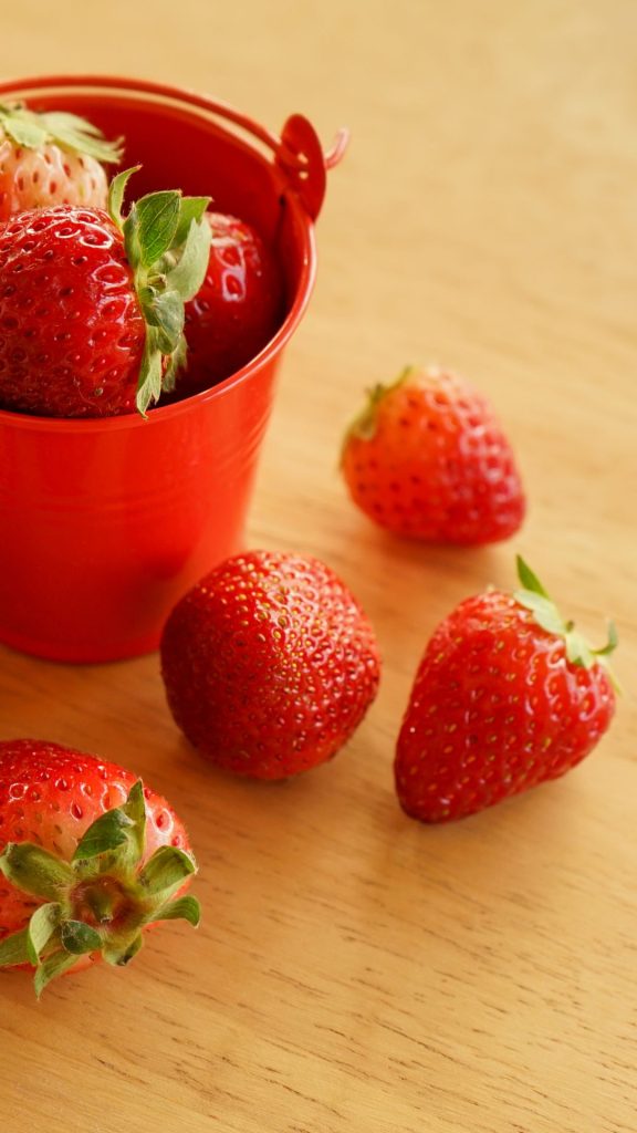 Red strawberries in red vintage basket on wooden table Strawberry Phone Wallpaper