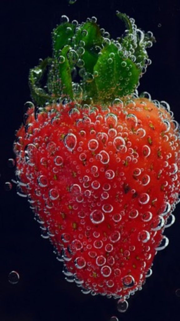 Red strawberry covered with water droplets in water strawberry phone wallpaper