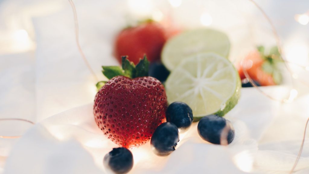 Strawberries with lemons and blueberries with fairy lights background strawberry wallpapers for laptop