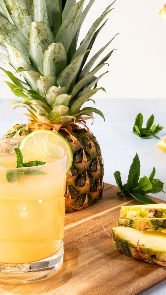 Fresh pineapple juice glass with lime placed on wooden platter with pineapple background Pineapple wallpaper