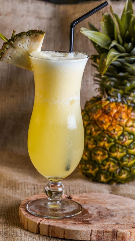 Fresh pineapple juice in cocktail glass with fresh pineapple chunk and blurred pineapple background Pineapple wallpaper