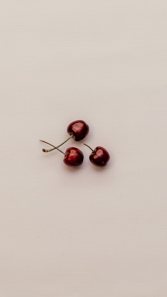 Minimal cherry wallpaper with three cherries in middle on baby pink background aesthetic cherry wallpapers