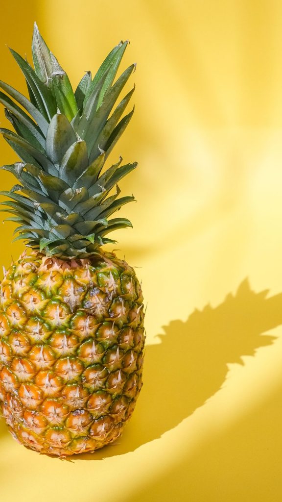Realistic photograph of fresh pineapple with shadow on plain yellow background Pineapple wallpaper