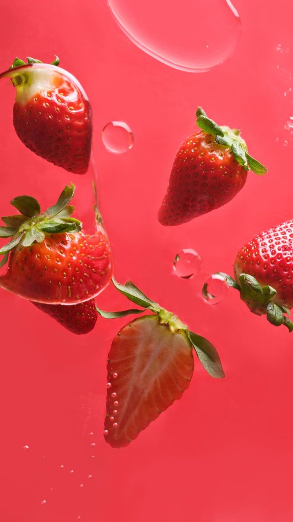 Red strawberries on pink horizon with water splashing Strawberry Background Wallpaper