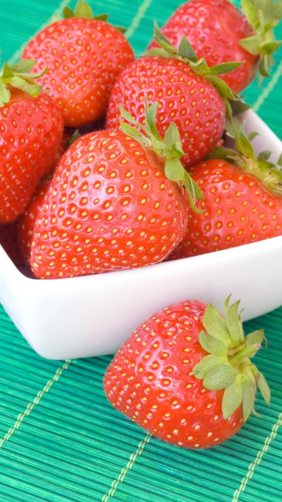 Strawberries in white bowl and blue bamboo sheet in the horizon Strawberry Background Wallpaper