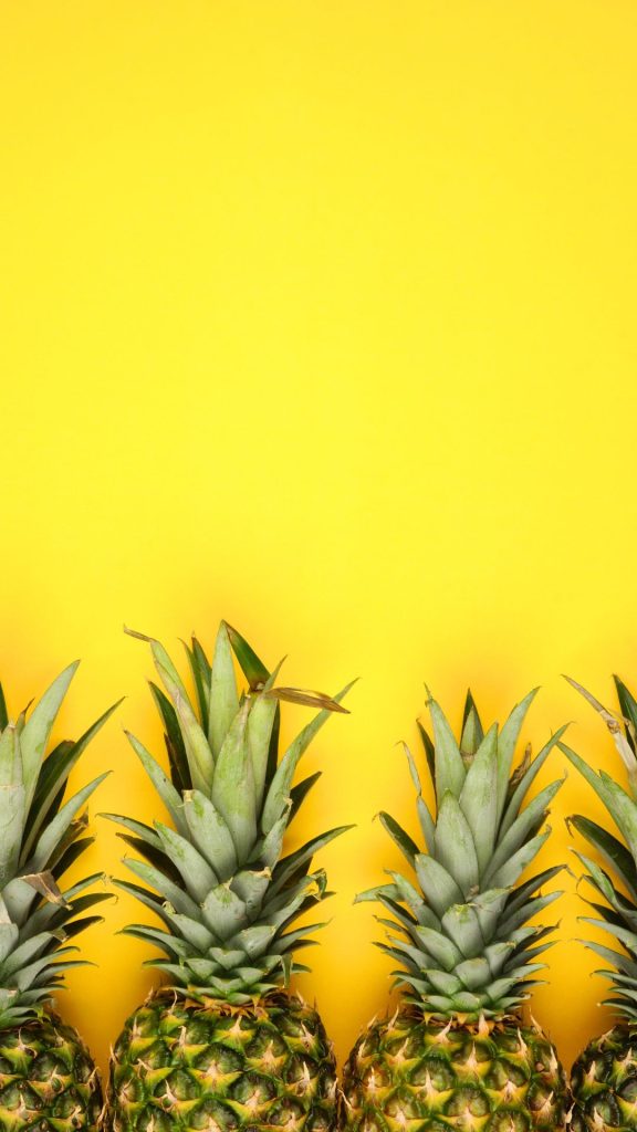 Sweet pineapples in line on yellow background still photograph Pineapple wallpaper