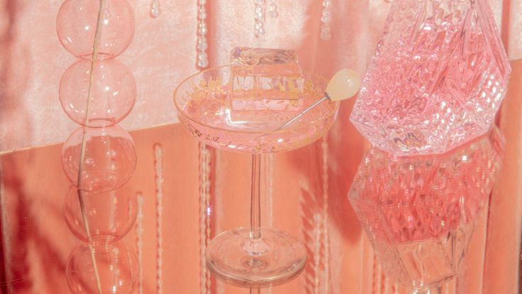 Luxurious glass and crystal drink setting in soft rose gold pink wallpaper