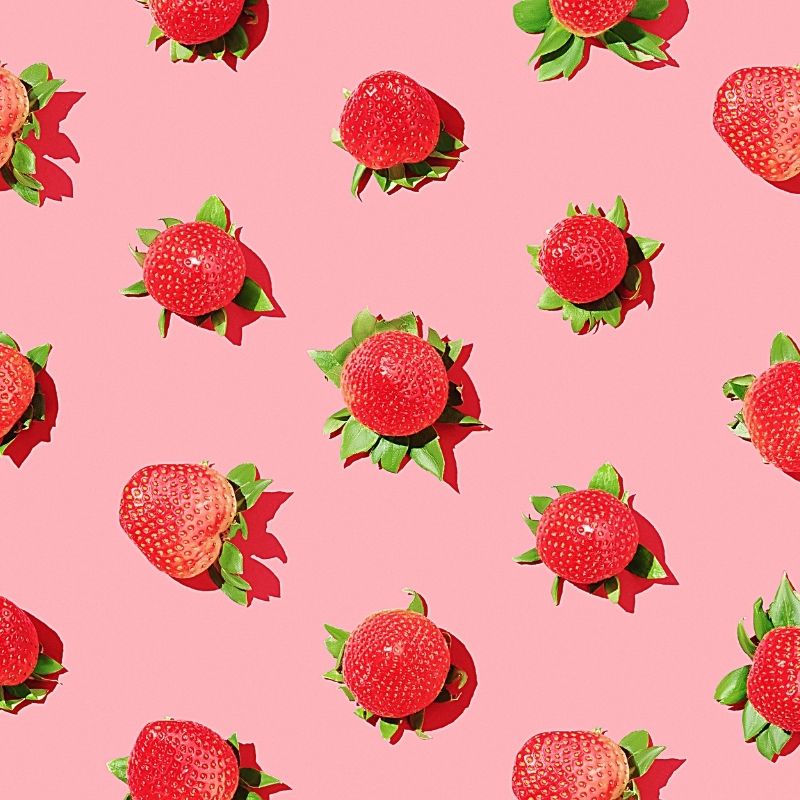 A cluster of vibrant strawberries set against a soft pink background